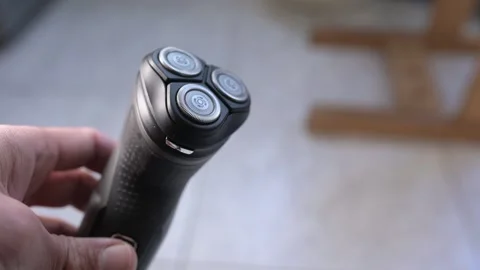 Close-up of an electric shaver turning on with buzzing motor sound, showing Stock Footage 319502976