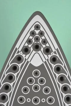 Close up of an electric steam iron tip on green background Stock Photos