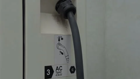 Close-up of electric vehicle charging connector plugged into public charging Stock Footage 344991027