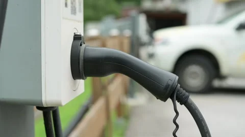 Close-up of electric vehicle charging plug connected to charging station, with Stock Footage 281535965