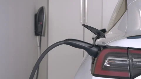 CLOSE UP: Electric vehicle connected to a charging station with a power cable Stock Footage 256111802