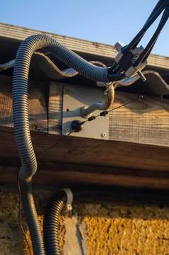 Close-up of electrical cables and conduits on an exterior wall under sunlig.. Stock Photos