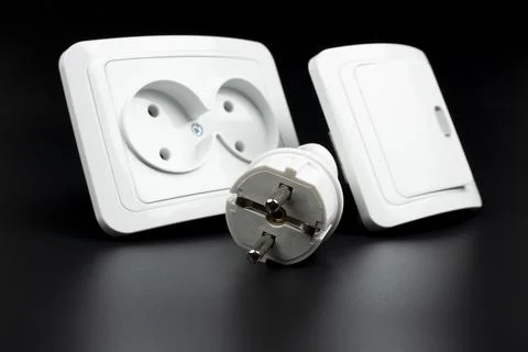 Close-up of electrical outlet, plug and light switch on black background Stock Photos