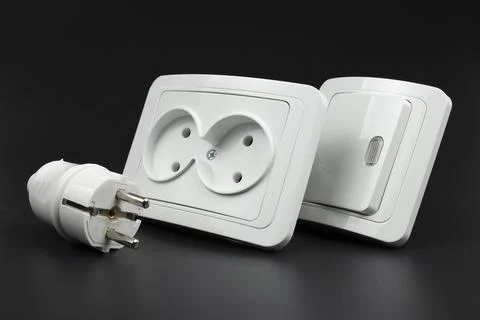 Close-up of electrical outlet, plug and light switch on black background Stock Photos