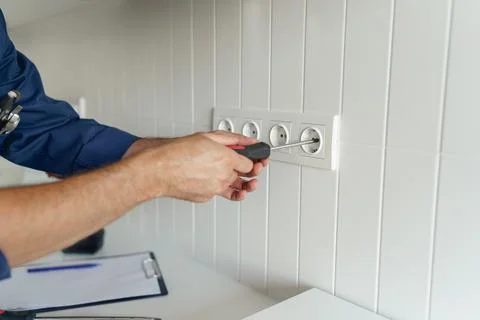 Close up of electrician using screwdriver while installing new electrical socket Stock Photos