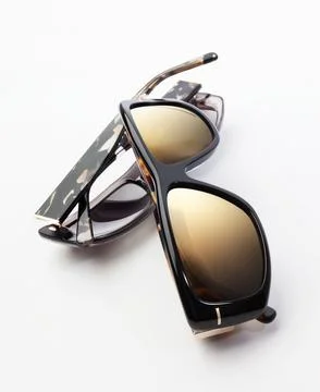Close up of elegant black and tortoiseshell sunglasses folded on white back.. Fotos de archivo