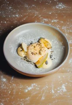 Close-up of elegant dish with egg, pear, and herbs on wooden surface Stock Photos