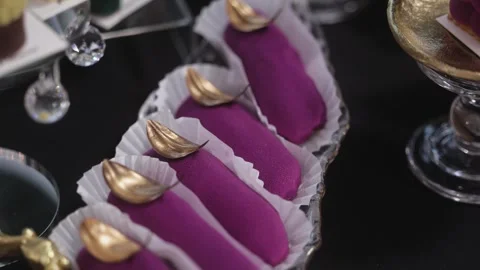Close-up of elegant purple mousse desserts with golden decoration on top, served Stock Footage 321048897