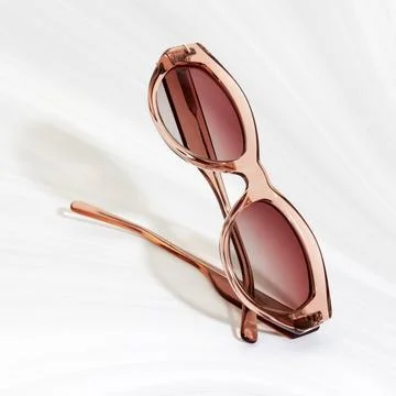 Close up of elegant translucent rose gold sunglasses on white textured back.. Stock Photos