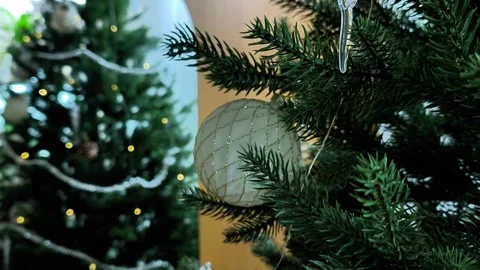 Close up elegant white bauble with gold grid pattern hanging on lush Christmas Stock Footage 344552259