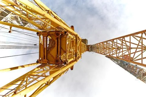 Close-up of elements of a yellow tower crane on a blue sky background. Stock Photos