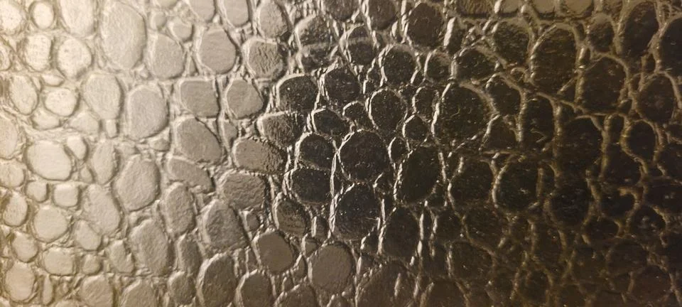 Close-up of embossed crocodile leather featuring an elegant bronze metallic.. Photos