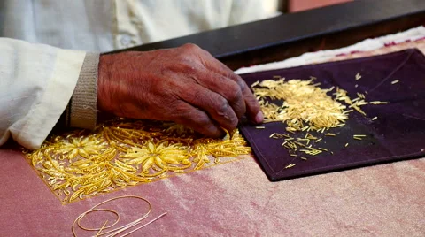 Close up embroider's hands carefully sewing golden beads into flower pattern Stock Footage 51362495