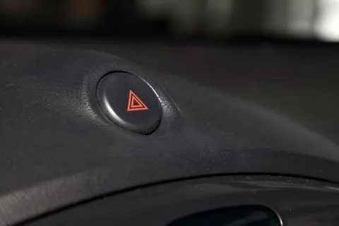 Close-up on emergency button with red triangle icon on the car dashboard. Pro Stock Photos