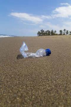 Close-up empty bottle plastic garbage on the sea beach. Stock Photos