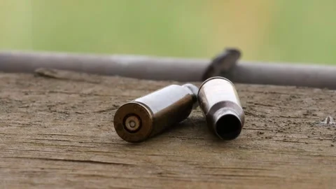 Close-up: empty bullet shells on rustic wooden table, ammunition casings Stock Footage 245934617