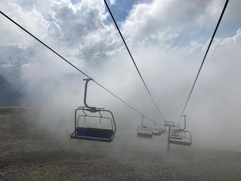 Close up of empty cableway in mountains. Modern ropeway with benches in cloud Stock Photos
