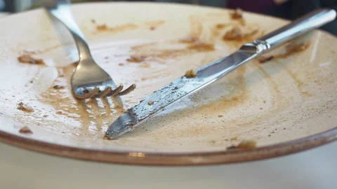 Close up of empty dirty ceramic plate with fork and knife after eating meal.. Stock Footage 332880022