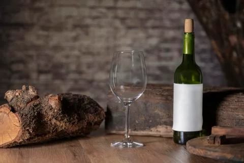 Close up of an empty glass surrounded by a bottle of wine and chunks of wood  Stock Photos
