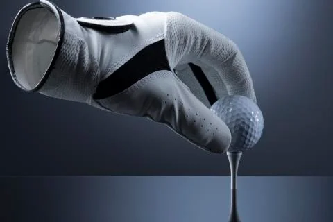 Close up of empty golf glove putting a golf ball on tee. Stock Photos