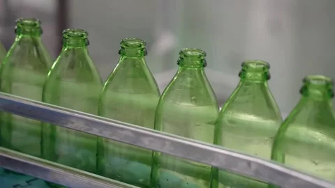 Close-up of empty green glass bottles moving on a high-speed conveyor belt in a Stockbeeldmateriaal 334274966