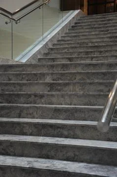 Close up of empty modern grey concrete staircase with metal and glass railing Stock Photos