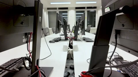 Close up of empty office desks with computer monitors and cables behind showing Stock Footage 325838869