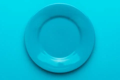 Close up of empty round blue plate on turquoise blue background with copy space Stock Photos