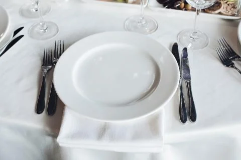 Close-up empty serving white big plate surrounded by knife fork ready to eating Stock Photos