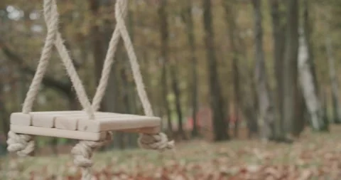 Close up of an empty swing swinging by wind in the middle of a desolate park in Stock Footage 140962915