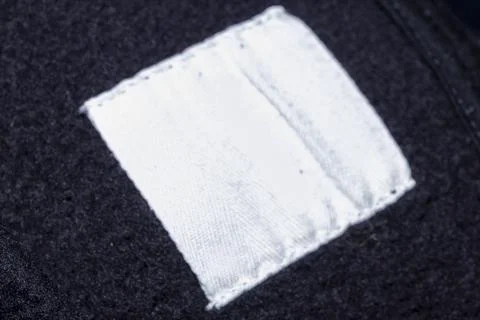 Close-up of an empty white fabric label on a black textile background, ideal for Stockfoto's