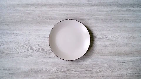 Close-up of an empty white plate on a light wooden background for the design.  Stock Footage 132166198