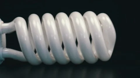 Close up of energy saving fluorescent light bulb on black table Stock Footage 105745278
