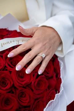 Close up of engagement ring on hand with red roses Stock Photos