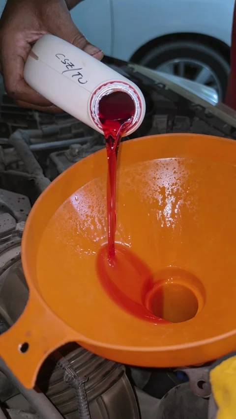 Close-up of engine oil being poured through a wide funnel into a vehicle Stock Footage 341554569