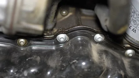 Close-up of engine oil pan with wet oil leaks around bolts. Stock Footage 345707511