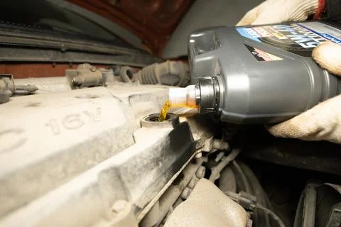 Close-up of engine oil pouring into the engine from a canister. A man pours new Stock Photos