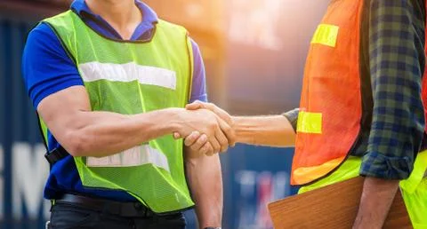 Close up of engineer and foreman worker handshake with blurred construction s Фото