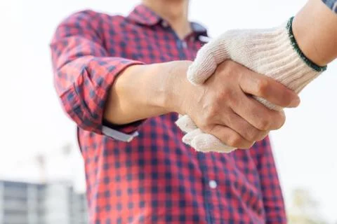 Close up of engineer and worker handshake with blurred construction site Фото