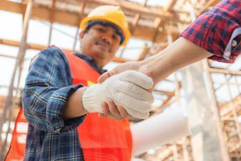 Close up of engineer and worker handshake with blurred construction site Фото