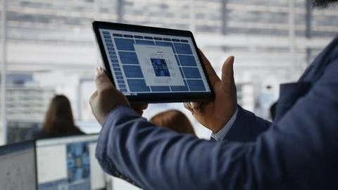 Close up of engineer examining microchip circuit layouts on tablet in factory Stock Photos