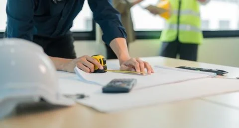 Close up engineer man working of sketching a construction project on his project Stock Photos