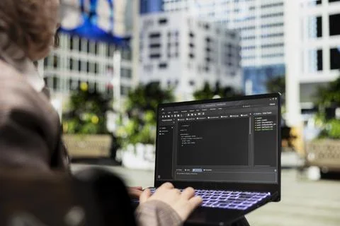 Close up of engineer on park bench writing code on laptop 写真素材