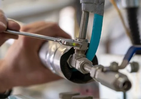 Close-up of an engineer performing pipeline adjustment with a wrench in an Stock Photos