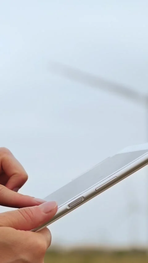 Close-up of engineer's hand using tablet to monitor wind turbines and renewable Stock Footage 341867629