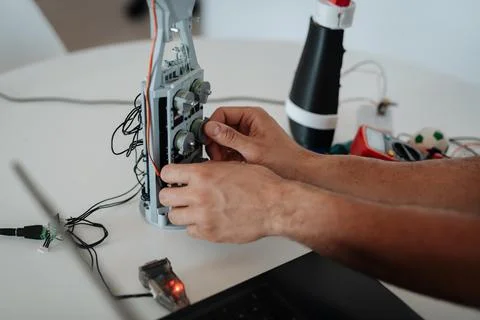 Close up of engineers hands building and programming a robotic arm at home. Stock Photos