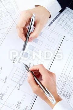 Close-up of engineers hands with pens over blueprints with sketches of projects Stock Photos
