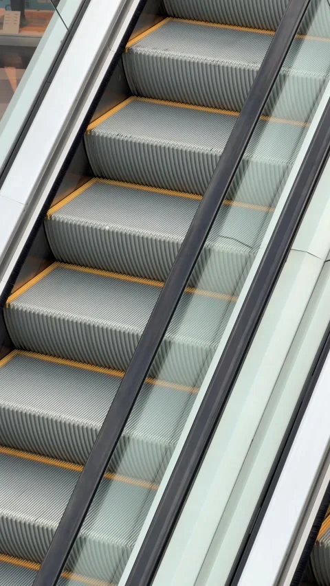 Close-up of an escalator moving upward. Gray steps with yellow edges. Glass.. Stock Footage 330991520