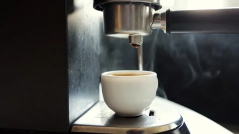 Close-up of espresso brewing in a white cup with steam rising from the machine Stock Footage 339000482