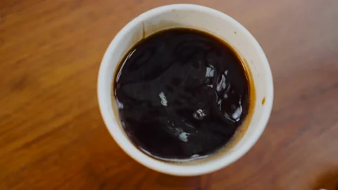 Close up espresso coffee drops fall into a filled disposable Cup from the coffee Video stock 141869341